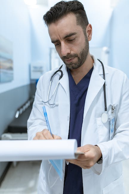 A male doctor in a hospital holding a clipboard.