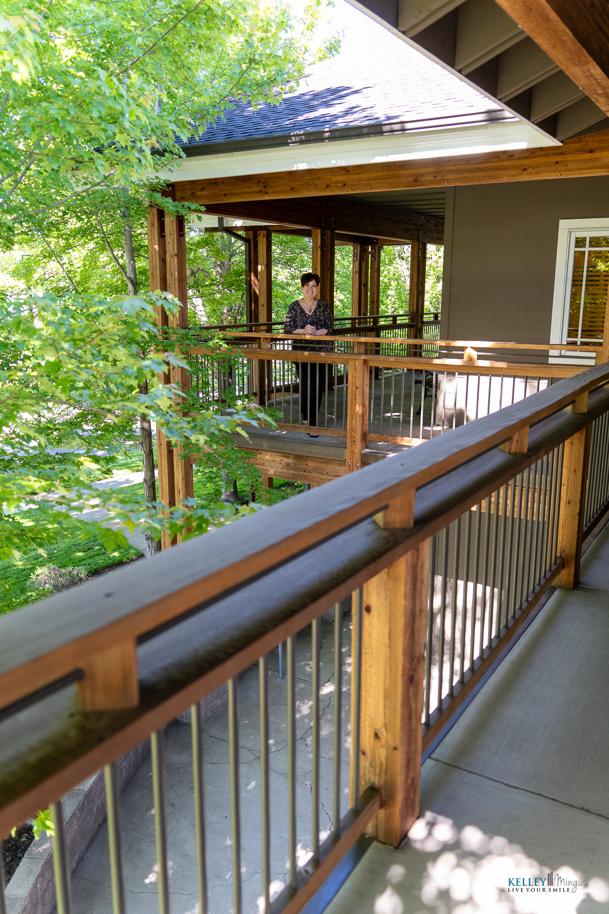 A person stands on a wooden balcony surrounded by green trees, with metal railings and a roof overhead, seeking a moment of calm from challenges like Binocular Vision Dysfunction (BVD) or Temporomandibular Joint (TMJ) disorders.